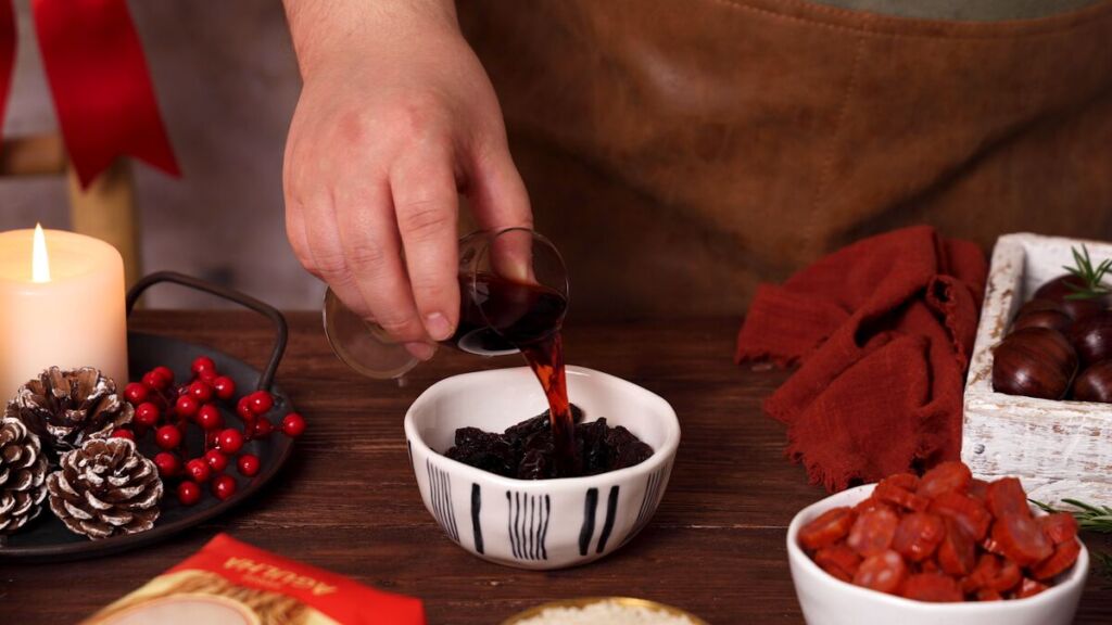 Comece por colocar as passas numa tigela e cubra-as com vinho do Porto