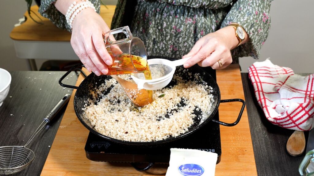 No mesmo recipiente, acrescentar o arroz e mexer até fritar um pouco e refresque com a infusão de açafrão